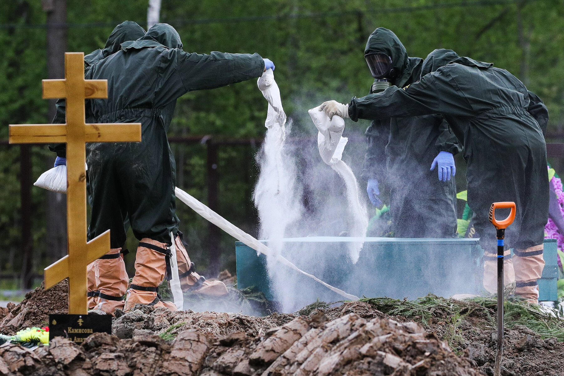 <p>Работники Бутовского кладбища засыпают могилу хлором во время похорон умерших после заражения коронавирусом</p>