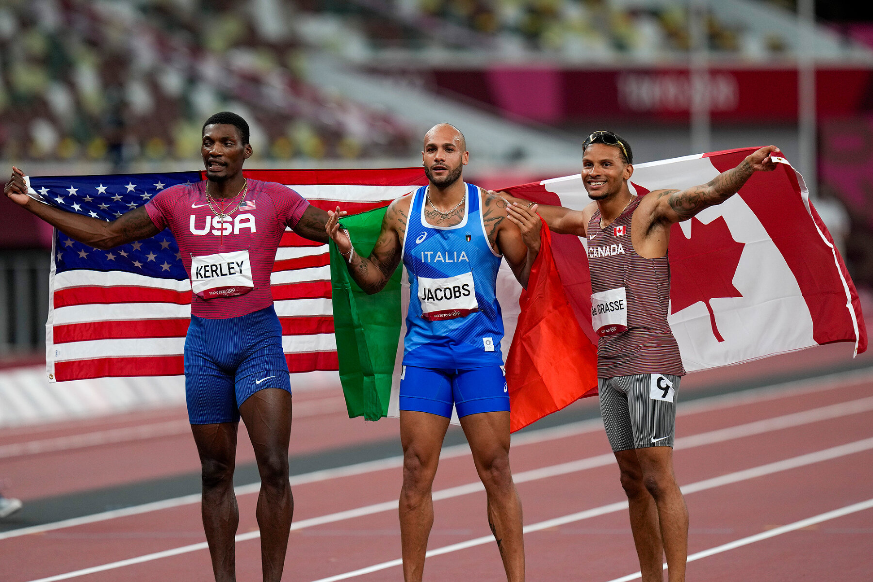 <p>Фред Керри из США (серебро), Марсель Джейкобс из Италии (золото) и Андре Де Грасс из Канады (бронза) празднуют взятие пьедестала в беге на 100 метров, 1 августа 2021 года</p>