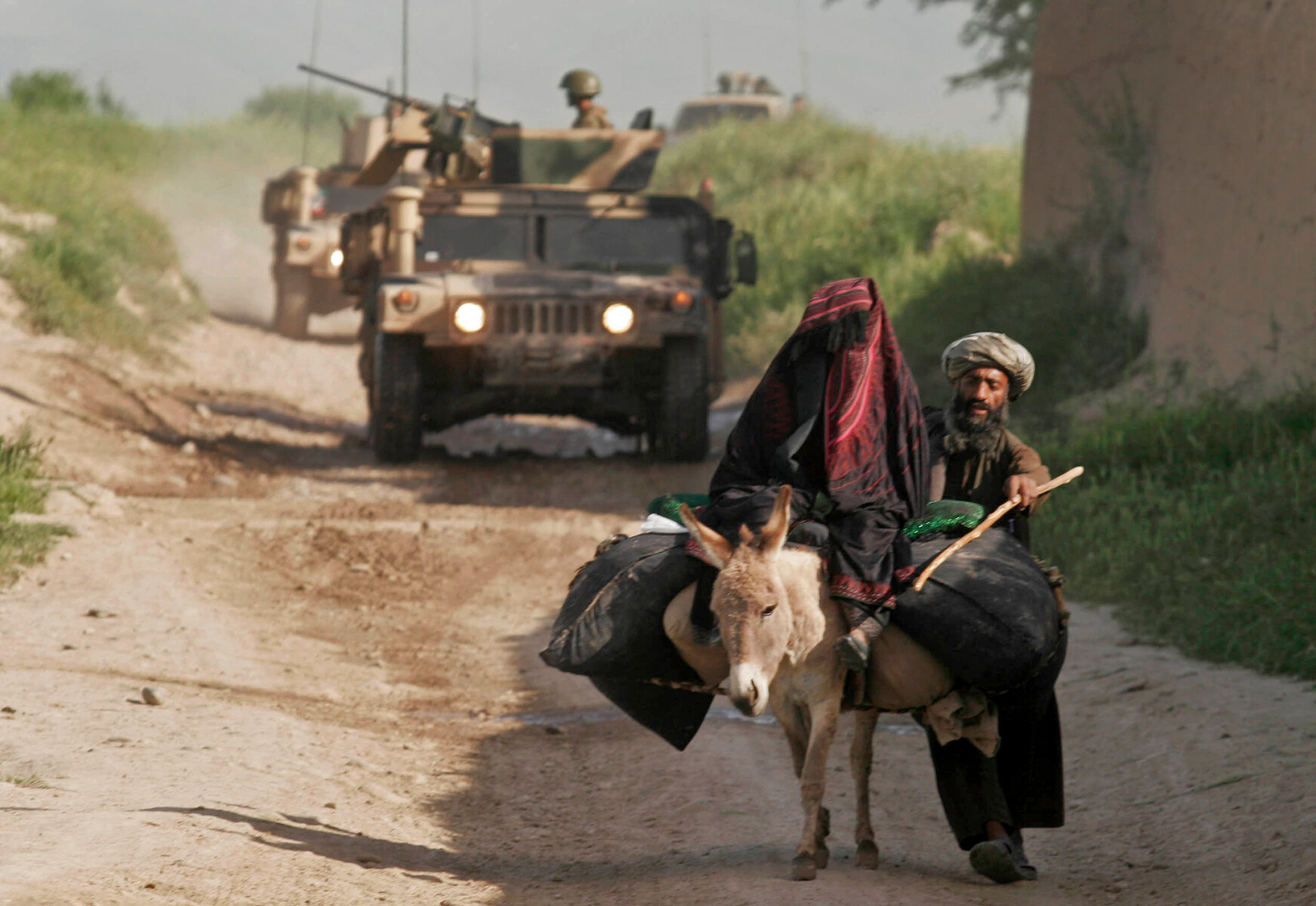 <p>Муж с женой едут по сельской дороге перед патрулем сил стран НАТО в провинции Бадгис к западу от Кабула, 21 апреля 2010 года</p>