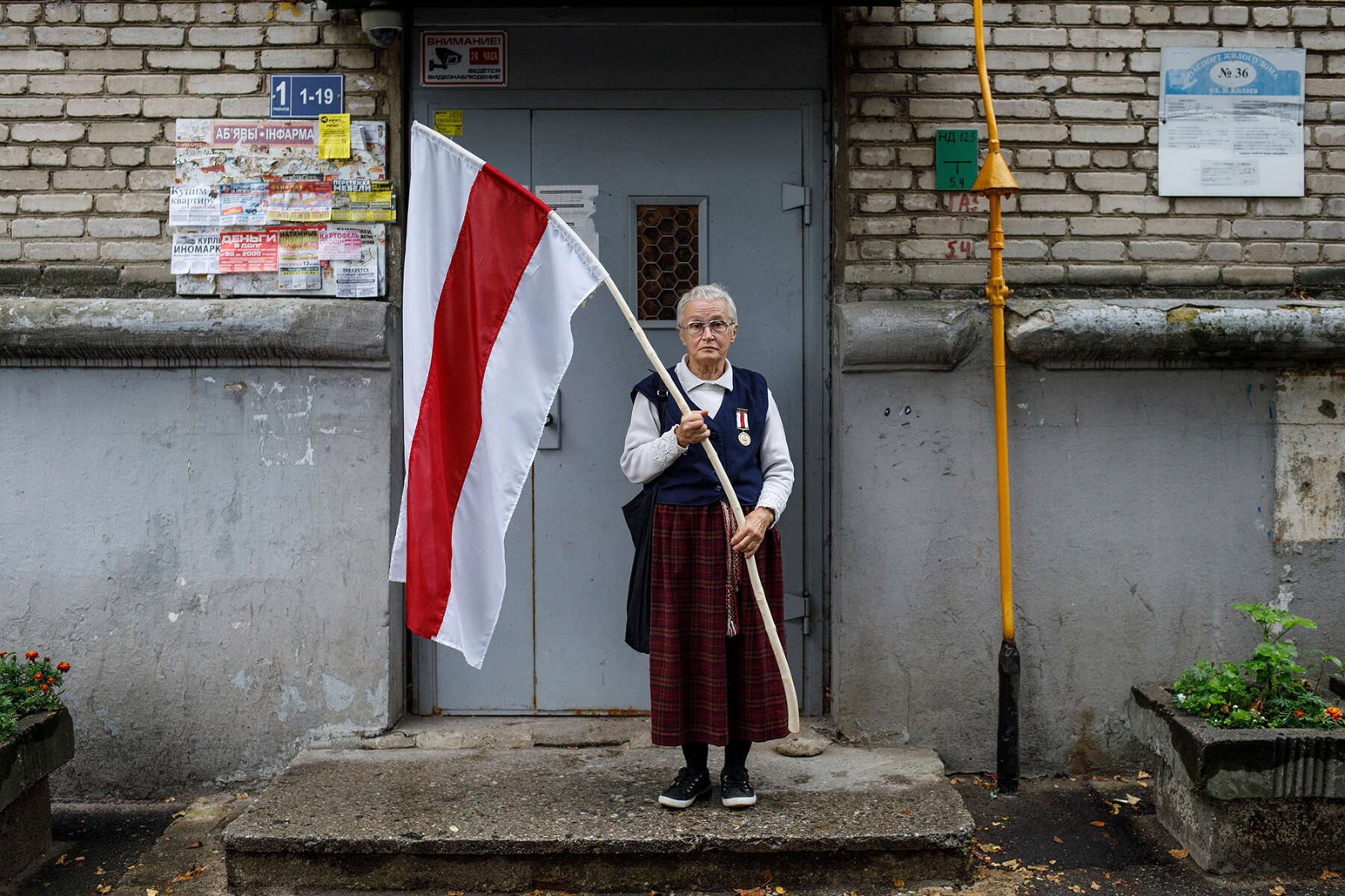 <p>Нина Багинская у подъезда своего дома перед акцией протеста, 10 сентября 2020 года.<br />
<br />
73-летняя Нина Багинская стала одним из символов белорусского протеста. Активистка получила широкую известность после видео, на котором она идет с бело-красно-белым флагом, ее пытается остановить силовик, а она говорит:&nbsp;&laquo;Я гуляю&raquo;. На самом деле она участвует в протестах с 1988 года. На протестах 2020 года ее неоднократно задерживали. Посмотреть ее интервью Дождю можно <a href="https://www.youtube.com/watch?v=6Icq3lUeh-k" target="_blank">здесь</a>.&nbsp;&nbsp;</p>