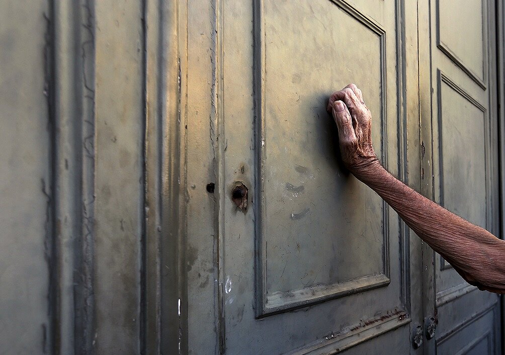 <p>Мужчина, ждущий получения части пенсии, прислонился к двери Национального банка в Афинах.&nbsp;7 июля 2015 года</p>