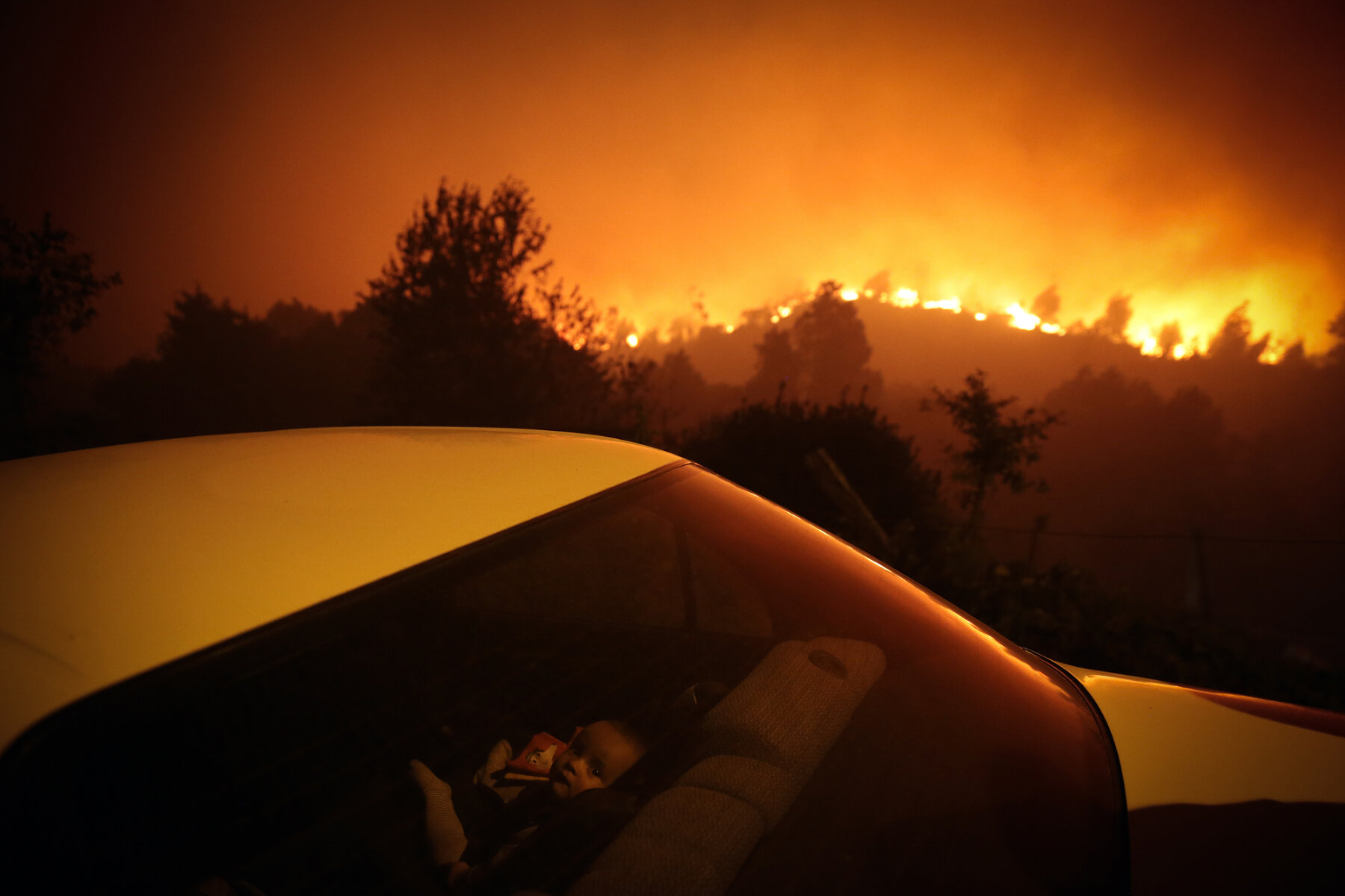 Forest Fire. <p>Номинация &laquo;Лучший снимок&raquo; в категории &laquo;Срочные новости&raquo;. Ребенок сидит в машине на фоне лесного пожара в Португалии</p>