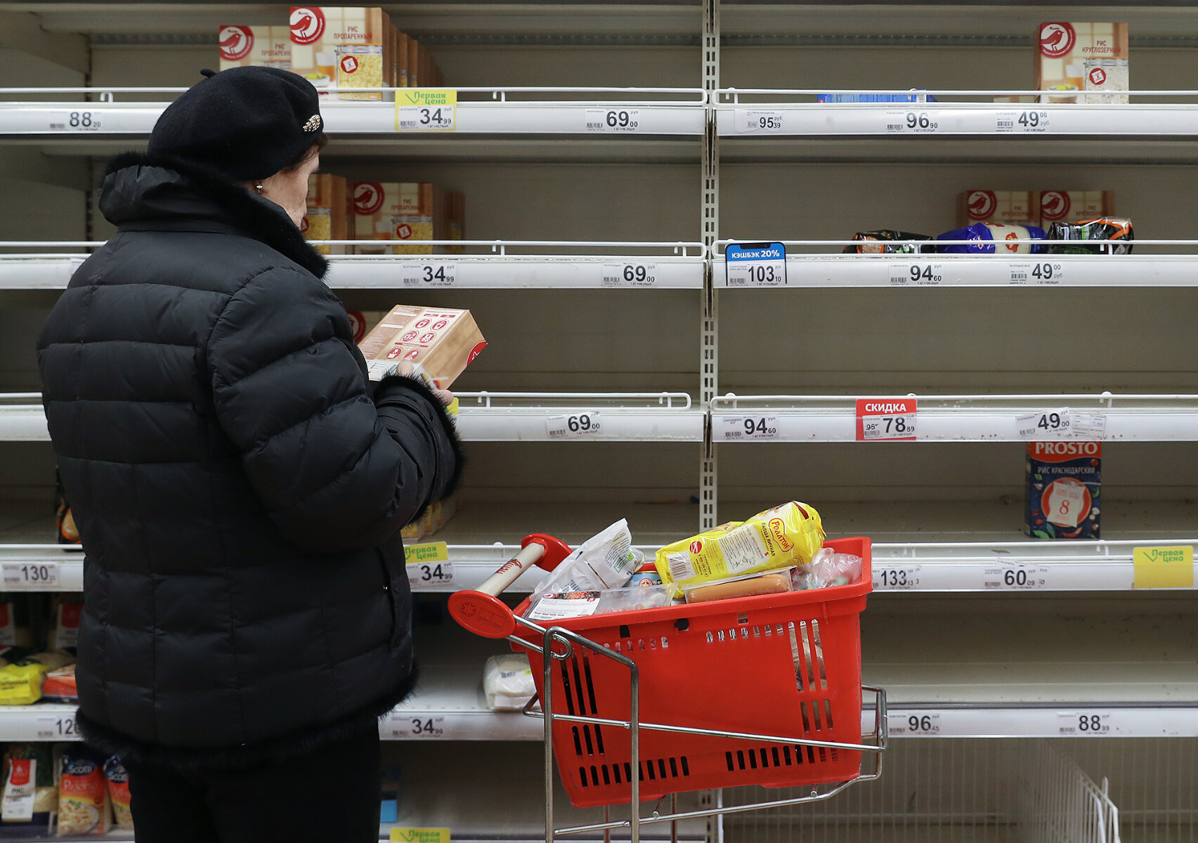 <p>Женщина выбирает продукты у полупустых полок в супермаркете в Рязани незадолго до режима полной самоизоляции</p>