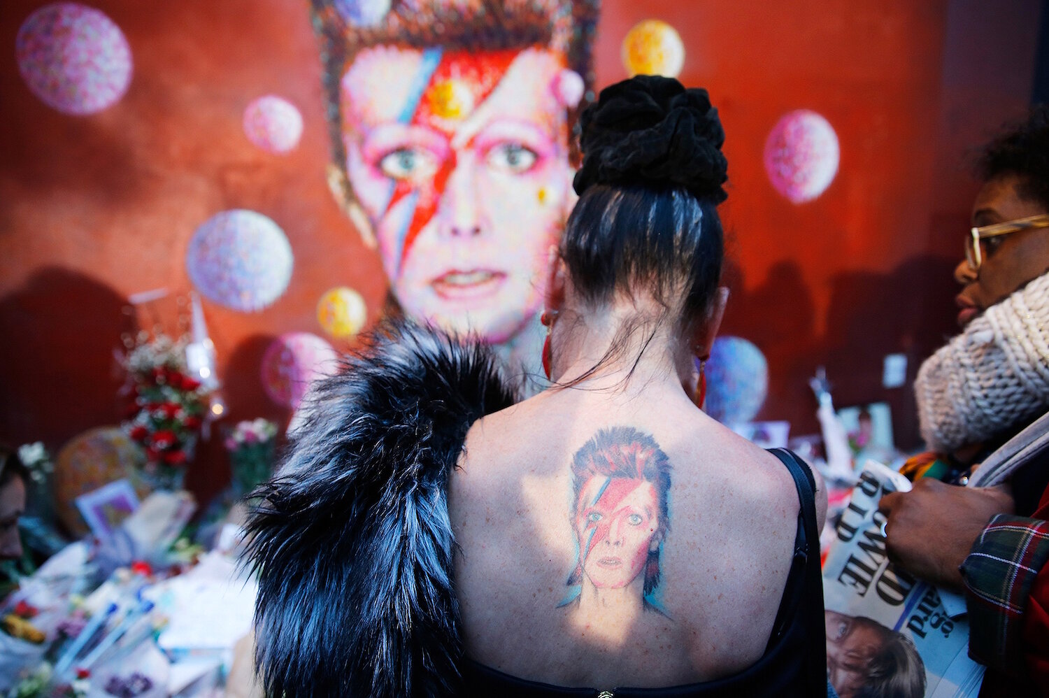 <p>11 января. Лондон, Великобритания. Женщина с татуировкой Зигги Стардаста &mdash; персонажа Дэвида Боуи &mdash; стоит у стены с таким же граффити и&nbsp;прощается&nbsp;с певцом, умершим от рака.</p>
