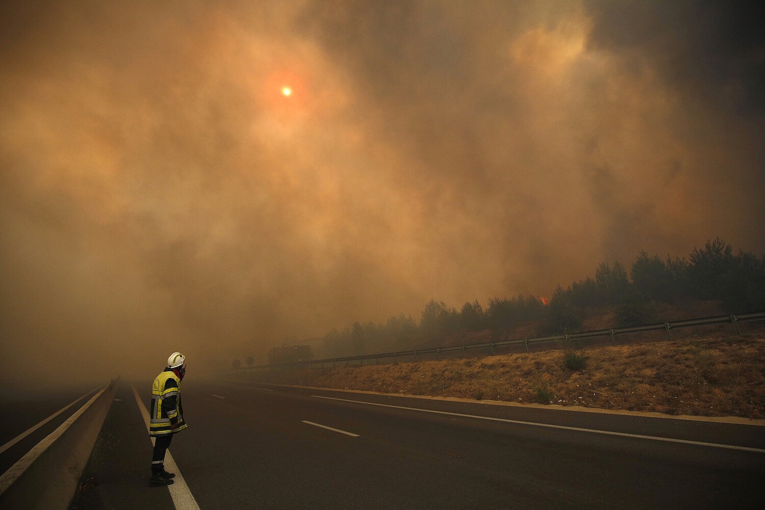 <p>10 августа. Марсель, Франция. Пожарный&nbsp;стоит на дороге, пока дым от сильного&nbsp;пожара застилает небо.</p>