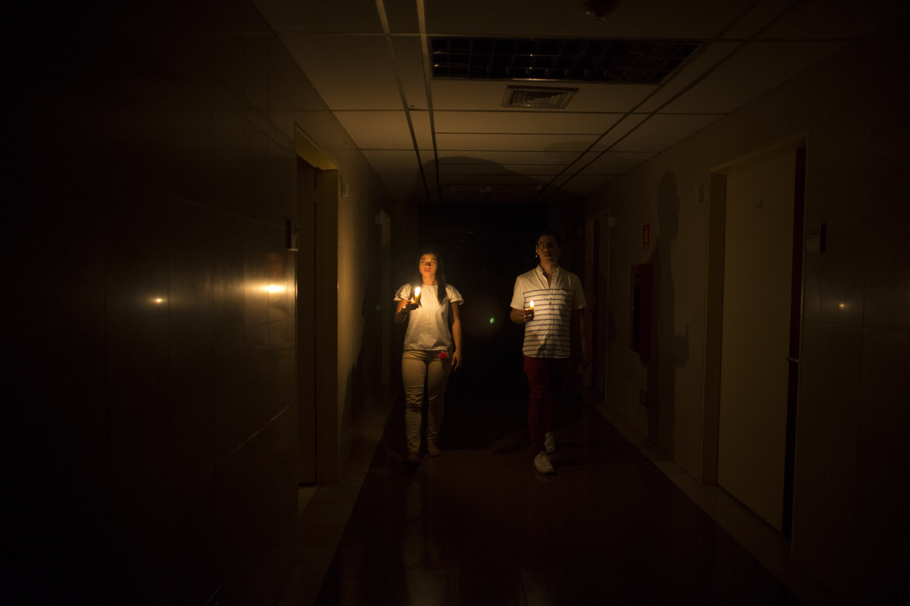 <p>Родственники пациента прогуливаются по коридору клиники со свечой, Каракас</p>