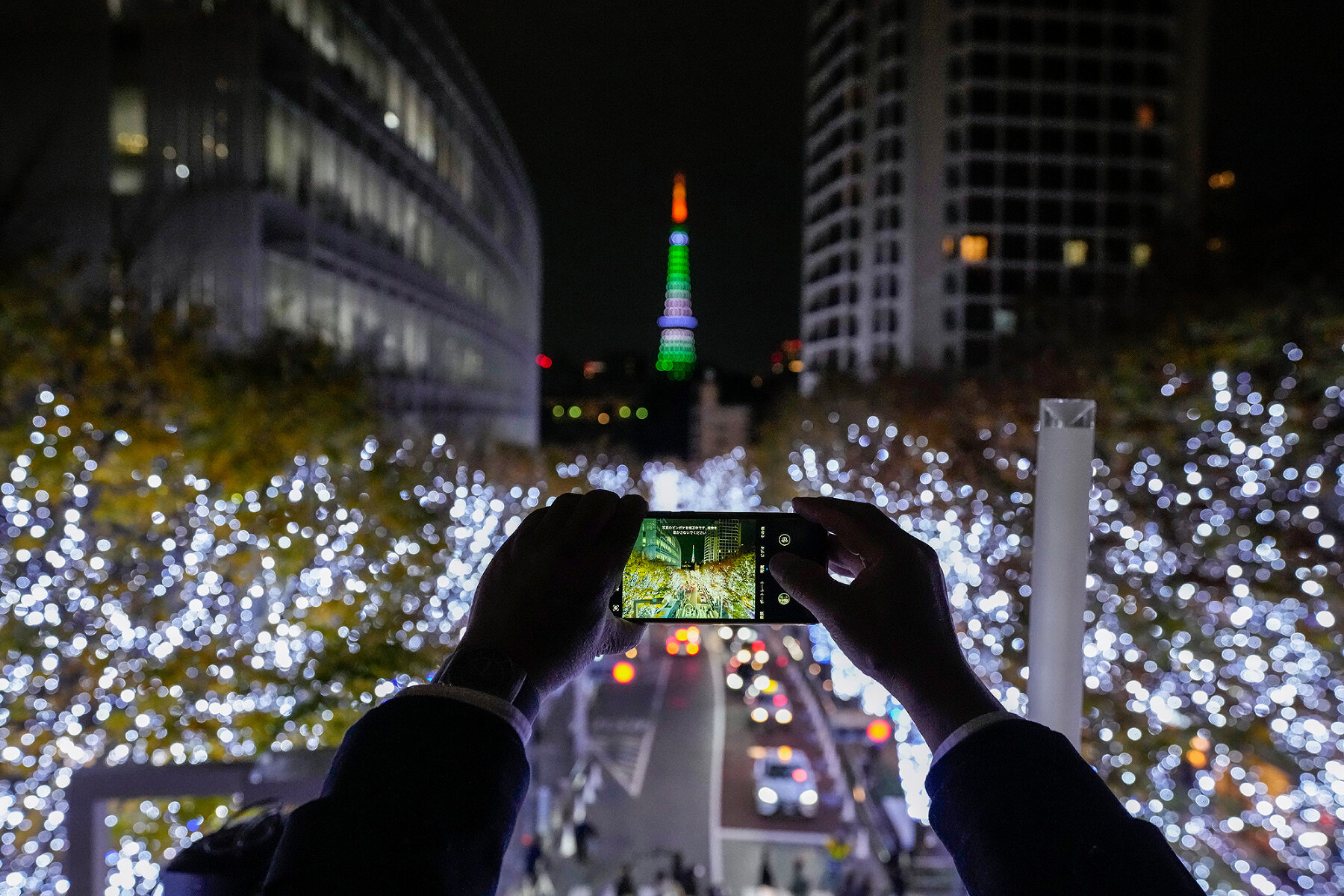 <p>Прохожий делает снимок празднично украшенной улицы в Токио, 7 декабря 2021 года</p>