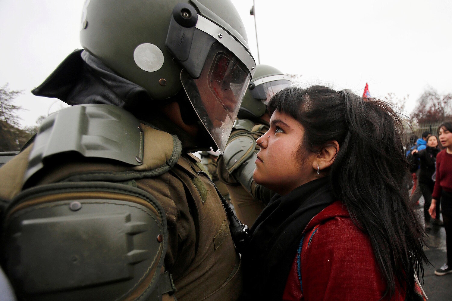 <p>11 сентября. Сантьяго, Чили. Участница&nbsp;протеста в честь годовщины военного переворота 1973 года смотрит на полицейского.</p>