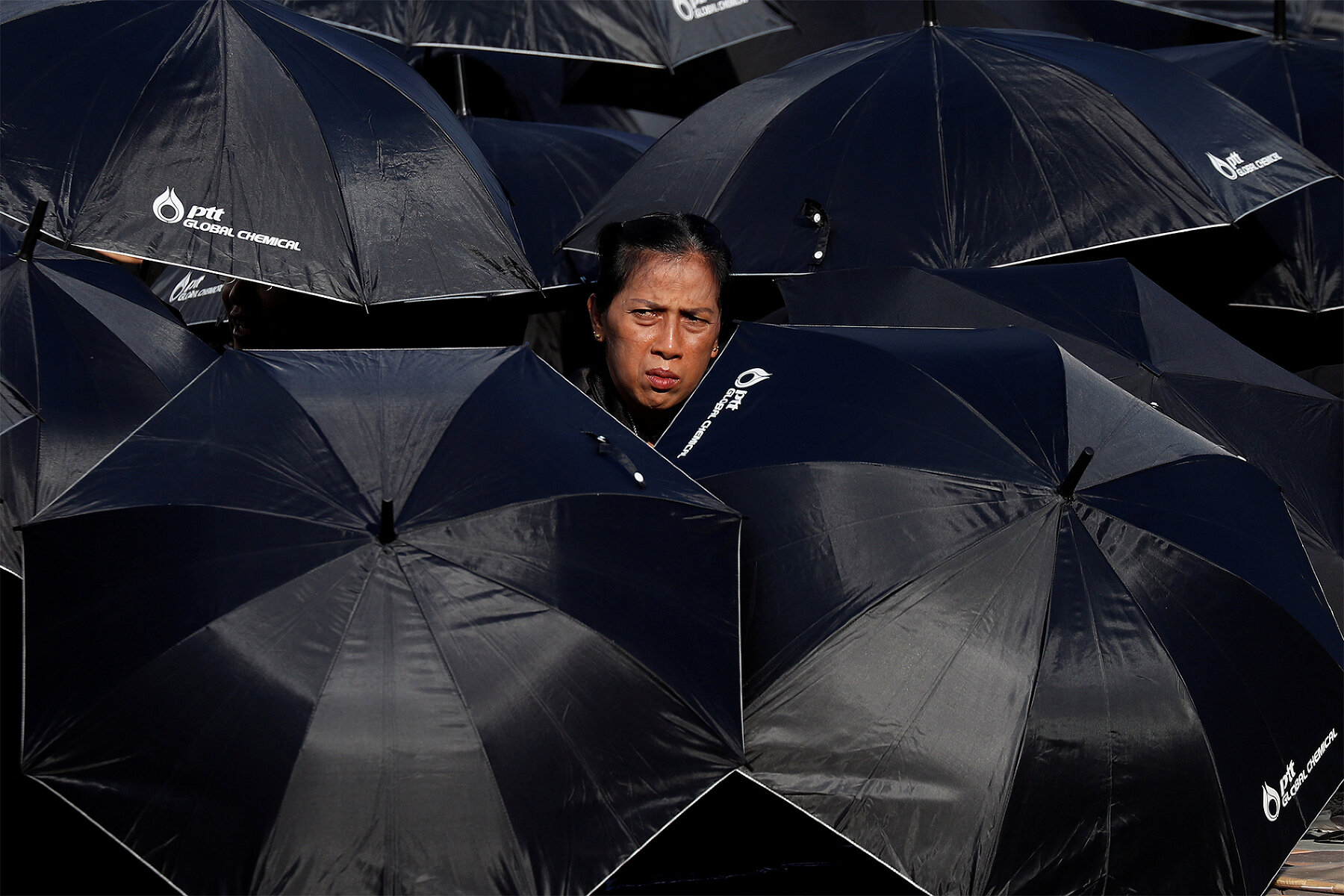 <p>Тайская женщина в окружении зонтов, которыми пришедшие посмотреть на церемонию закрываются от солнца.&nbsp;</p>