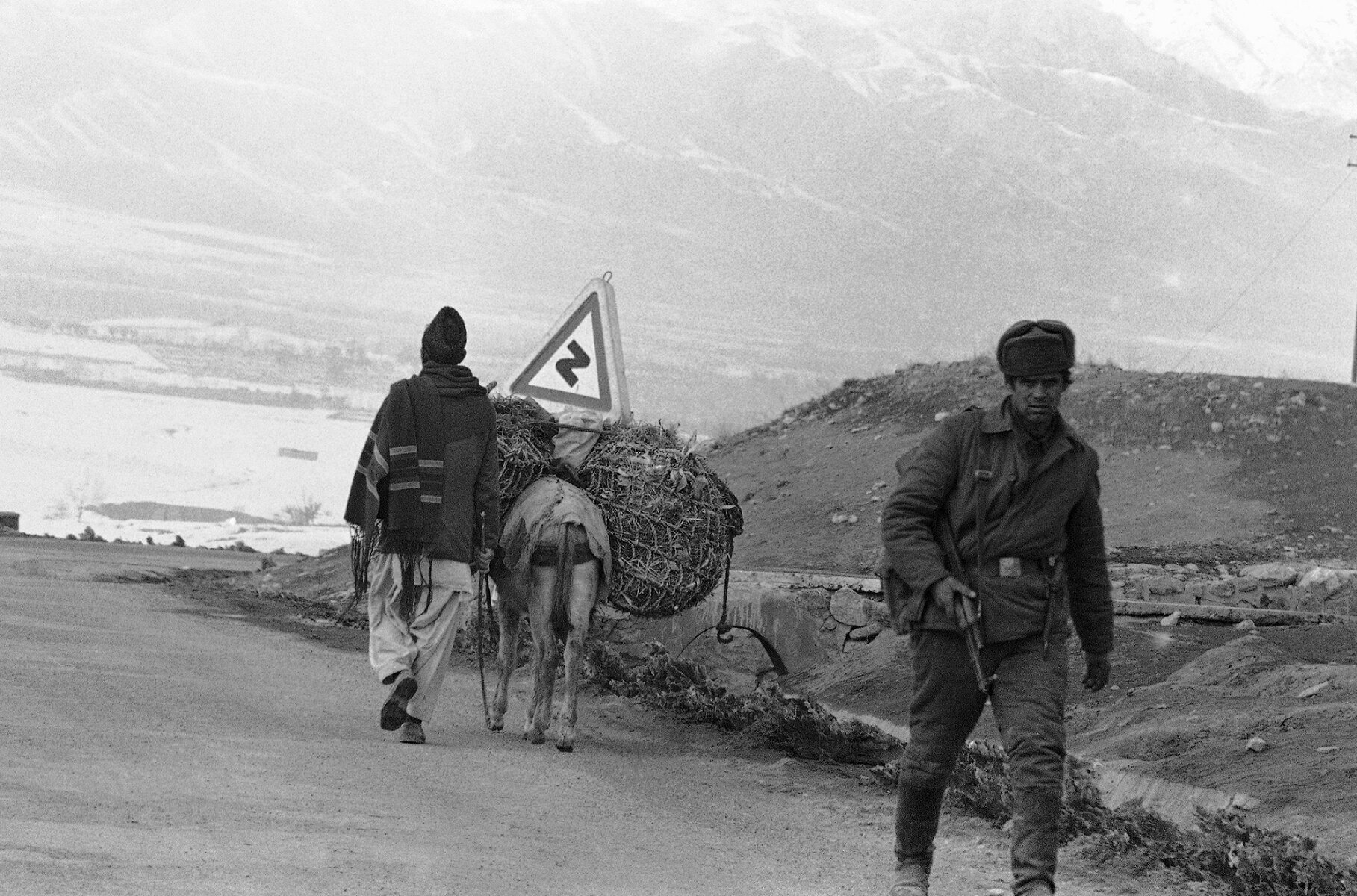<p>Советский патрульный и местный житель с нагруженным поклажей ослом на горной дороге недалеко от Кабула, 8 января 1980 года</p>