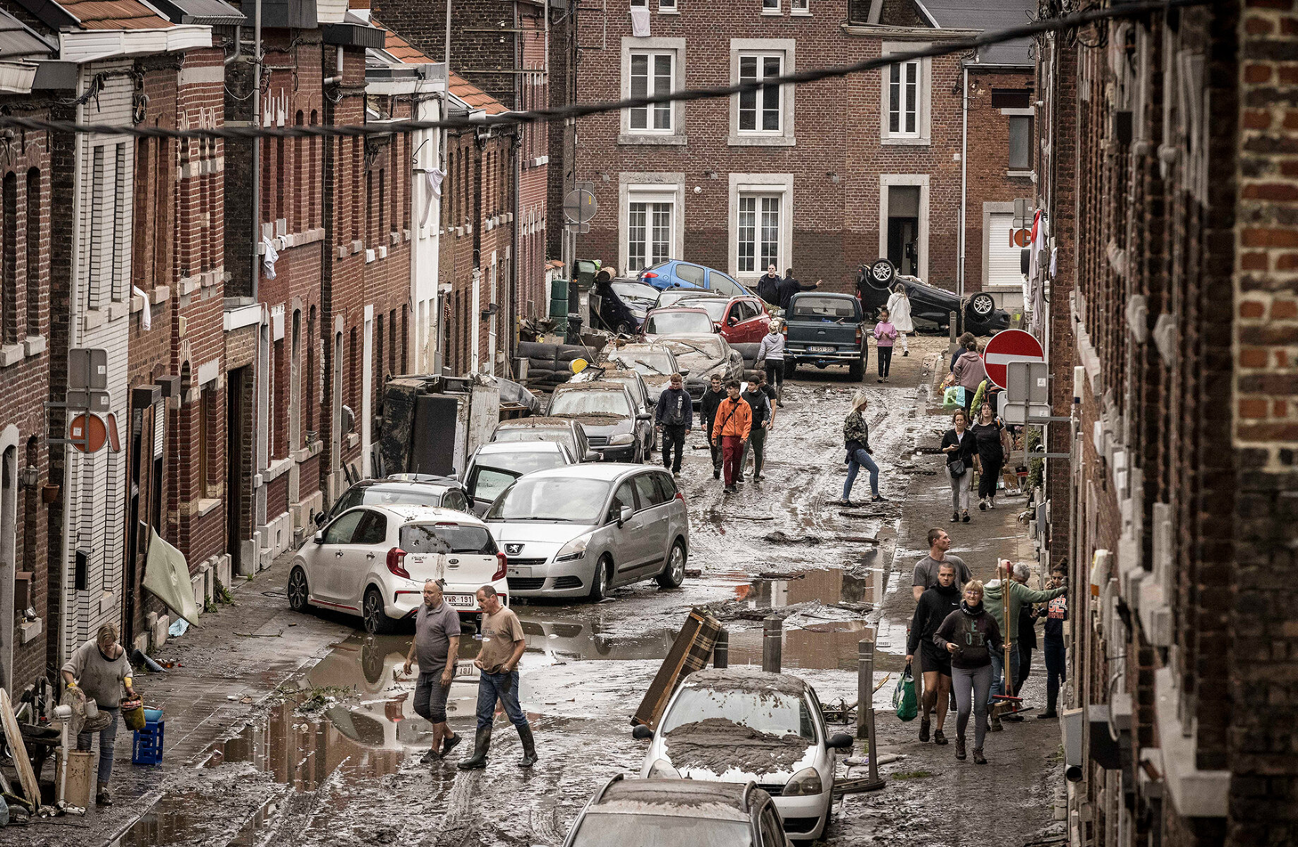 <p>Местные жители идут через улицу, поврежденную наводнением в коммуне Шене, Льеж, Бельгия</p>