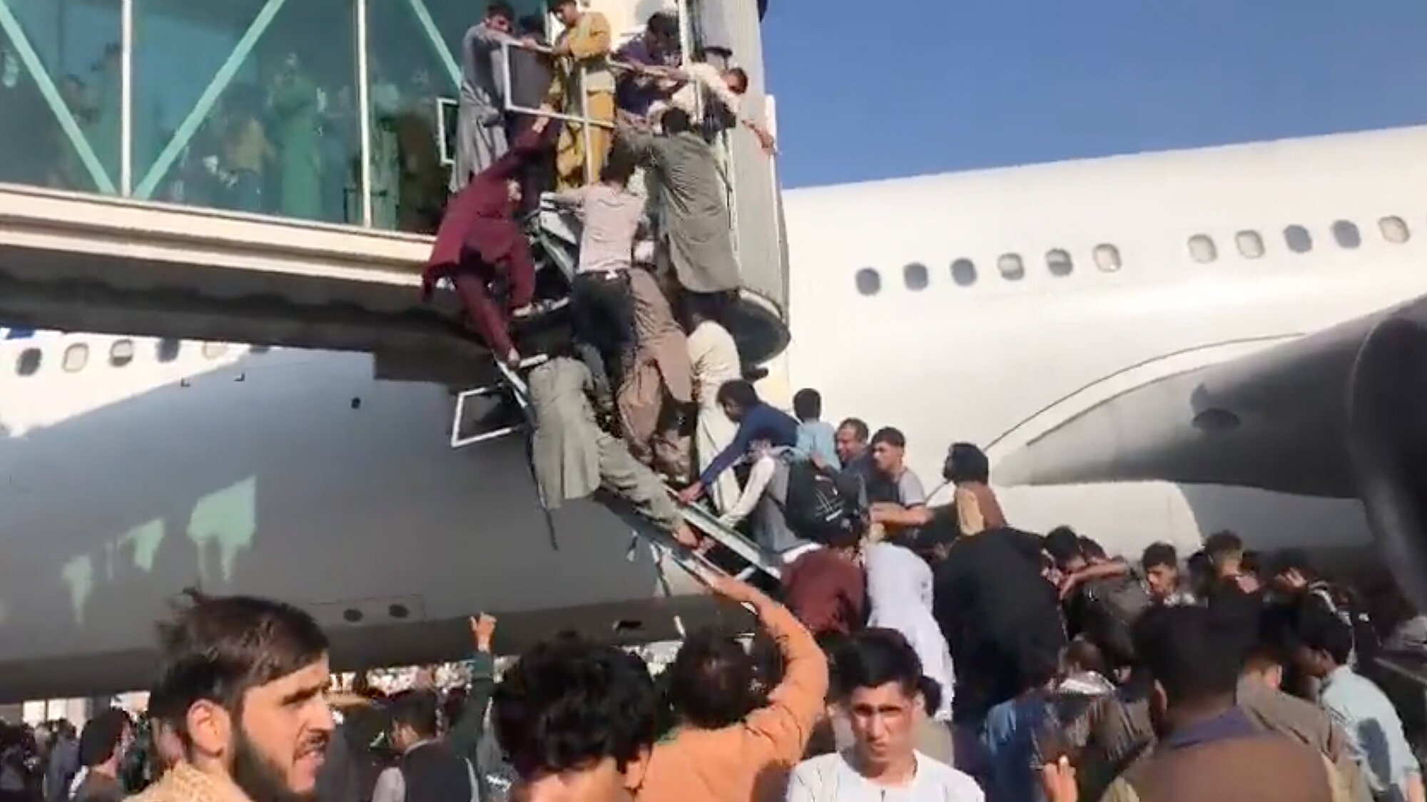 <p>Местные жители пытаются забраться в самолет на взлетной полосе в аэропорту Кабула, 16 августа 2021 года</p>