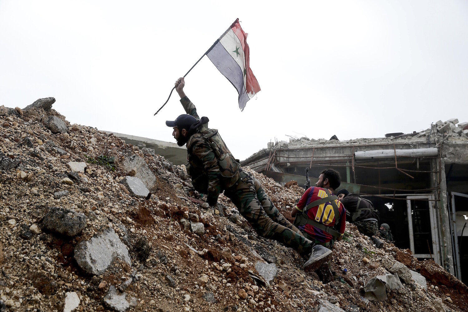 <p>5 декабря.&nbsp;Алеппо, Сирия. Сирийский солдат ставит национальный флаг Сирии во время боя с боевиками на линии фронта.</p>