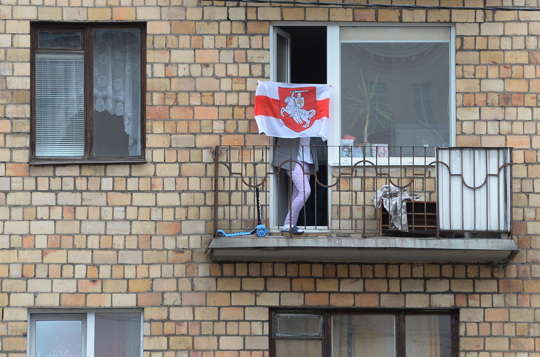 <p>Жительница Минска&nbsp;на балконе&nbsp;дома с бело-красно-белым флагом во время женского марша, 17 октября 2020 года.<br />
<br />
Бело-красно-белый флаг стал одним&nbsp;из главных символов протеста против режима Лукашенко. При этом он был символом&nbsp;белорусского движения за независимость страны еще на рубеже XIX-XX веков. Несмотря на то, что сейчас Лукашенко называет этот флаг&nbsp;&laquo;фашистким&raquo;, именно под ним он давал присягу после избрания президентом&nbsp;в 1994 году. После начала протестов в 2020 году власти Беларуси объявили настоящую войну символике этого цвета. За флаг могли задержать, арестовать, эти цвета закрашивали везде, где только можно.&nbsp;Доходило до абсурда: человека могли задержать&nbsp;за коробку от телевизора LG бело-красно-белого цвета (нет, <a href="https://tvrain.ru/news/zhitelja_minska_zaderzhali_za_belo_krasnuju_korobku_iz_pod_televizora_v_okne-528986/" target="_blank">это не шутка</a>). В итоге весной этого года МВД предложило включить бело-красно-белый флаг&nbsp;в список запрещенной нацистской символики, потому что&nbsp;во время Великой Отечественной войны его использовали белорусские коллаборационисты (<a href="https://tvrain.ru/news/mvd_belarusi_predlozhilo_priznat_belo_krasno_belyj_flag_natsistskoj_simvolikoj-530388/" target="_blank">но не только они</a>).&nbsp;</p>