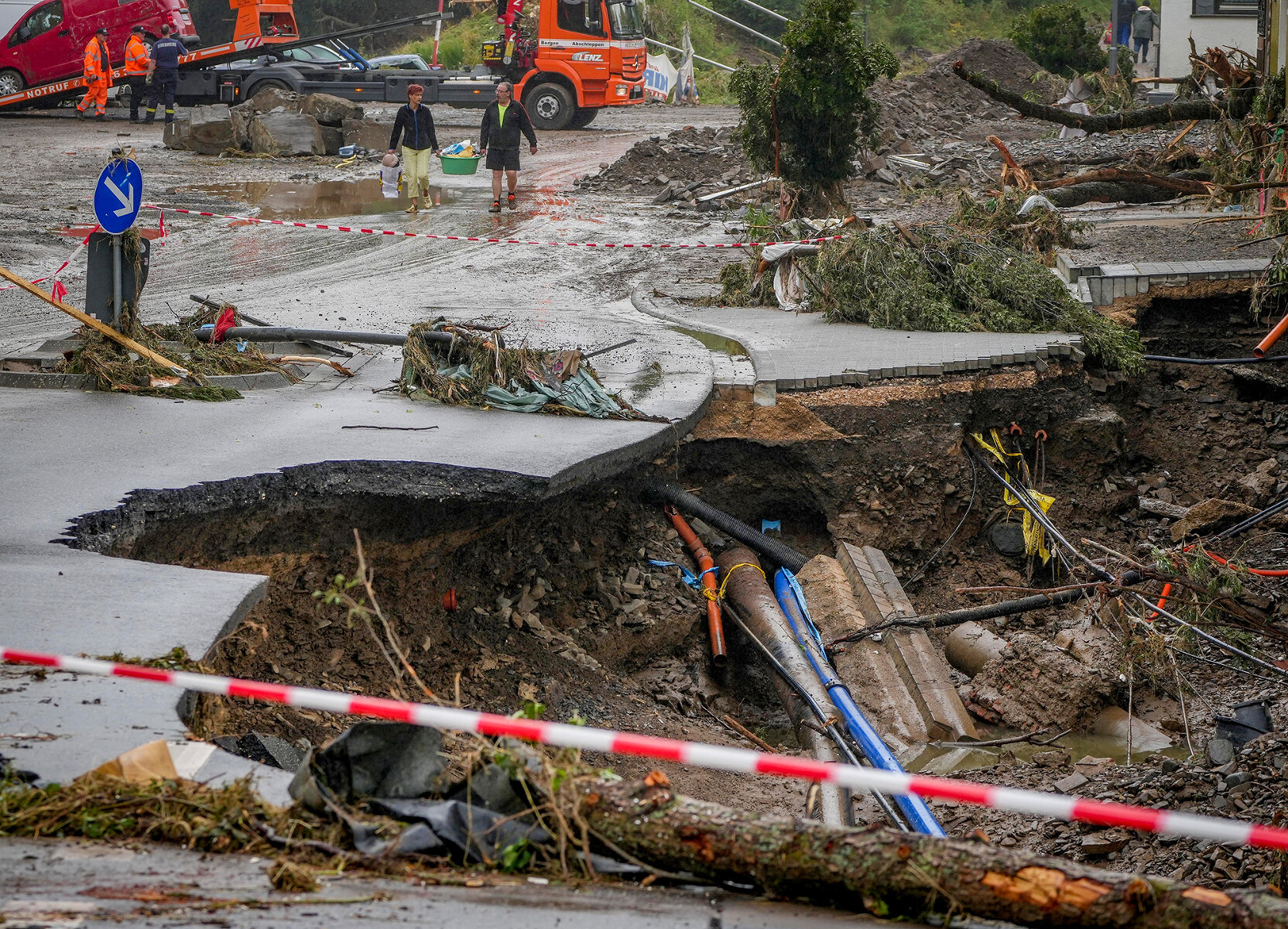 <p>Местные жители несут вещи вдоль дороги, поврежденной наводнением&nbsp;в городке Шульд,&nbsp;Рейнланд-Пфальц, Германия</p>
