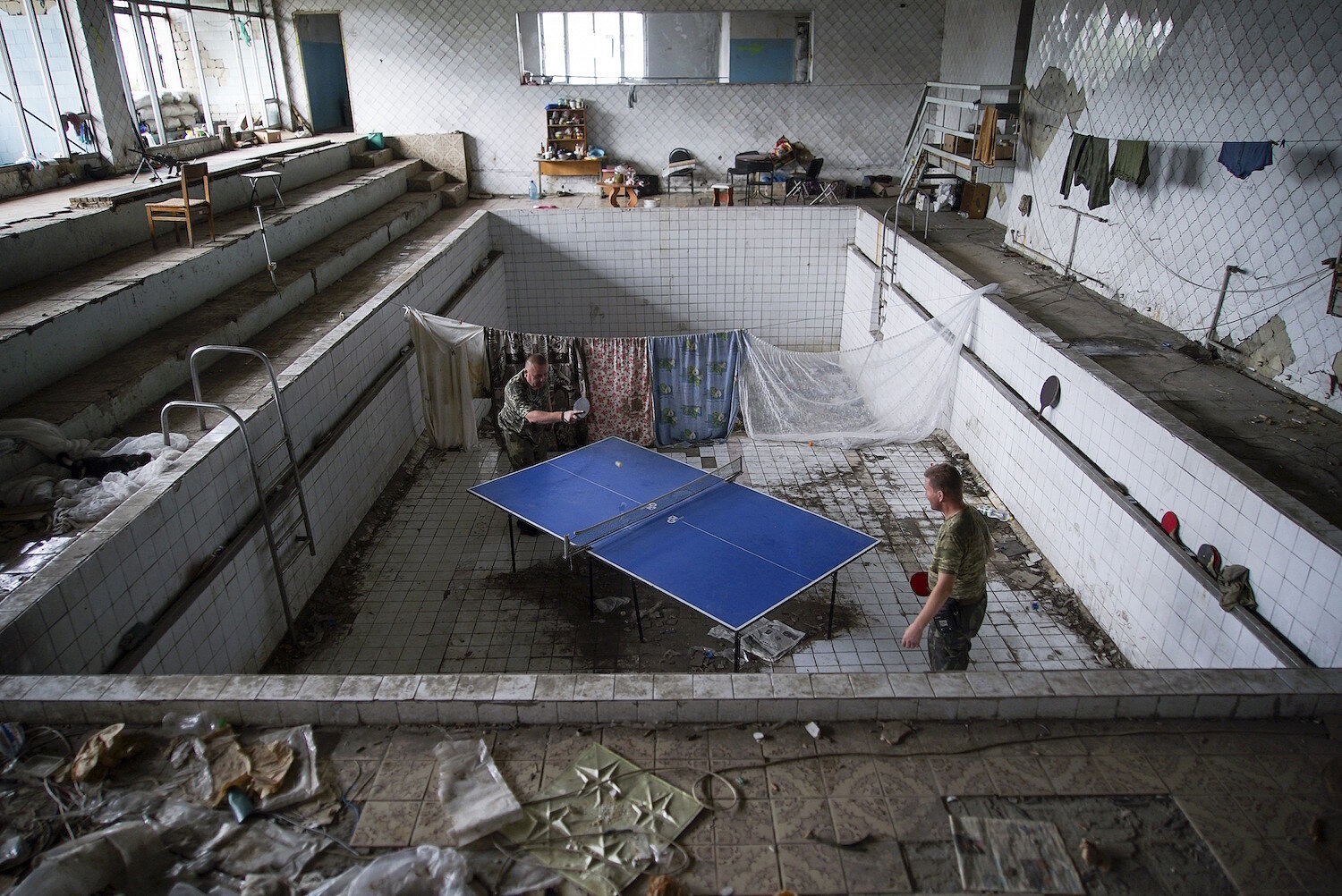 <p>25 августа. Марьинка, Украина. Украинские солдаты играют в настольный теннис в разрушенном бассейне. По оценкам ООН, более 9,5 тысяч человек были убиты в ходе боевых действий на востоке Украины с апреля 2014 года.</p>