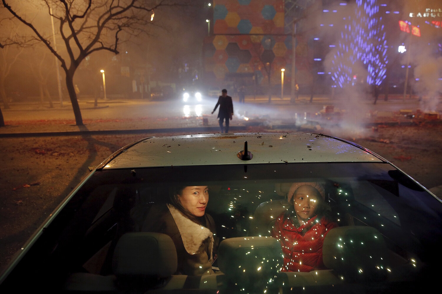 <p>7 февраля. Пекин, Китай.&nbsp;Женщина с дочкой сидят в машине во время фейерверков и праздничного салюта в честь китайского нового года.</p>