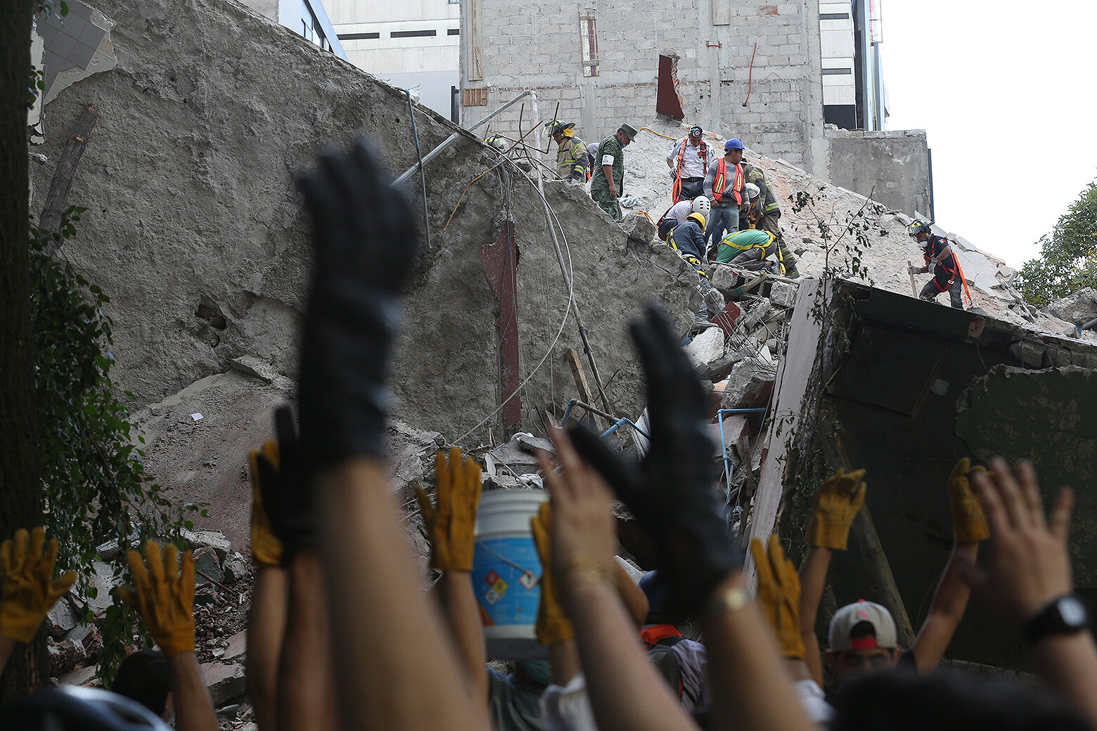 <p>Спасатели поднимают руки с просьбой о тишине&nbsp;при разборе рухнувшего здания и поиске жертв.</p>